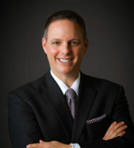 Here's an alt tag for the image: `Headshot of a man in a suit`