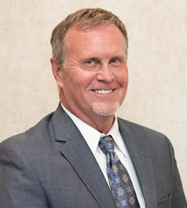 Here's an alt tag for the image: `Headshot of a man in a suit`