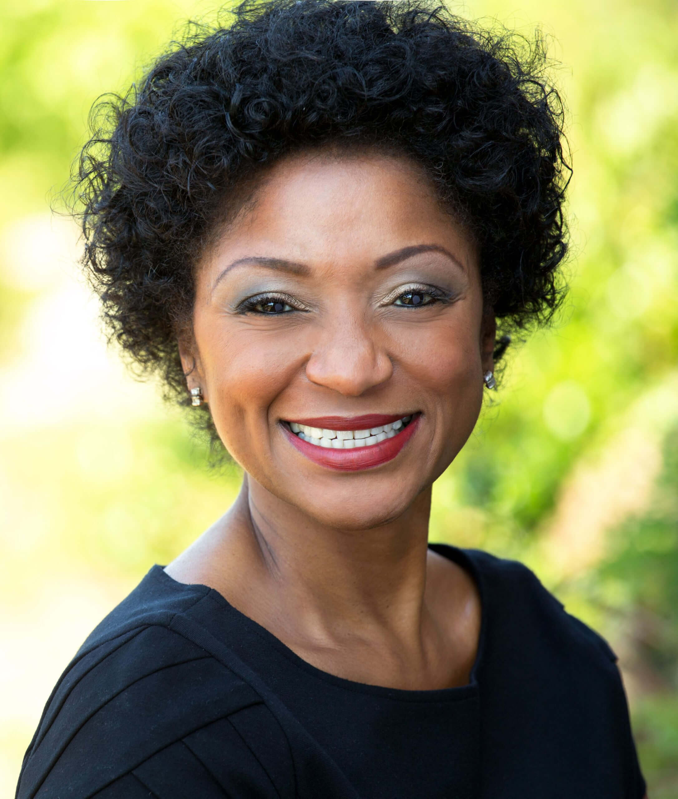 Smiling Black woman with curly hair.