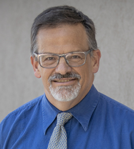 Here's an alt tag for the image: Headshot of man in blue shirt and tie.