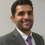 Here's an alt tag for the image: Headshot of a man in a suit.